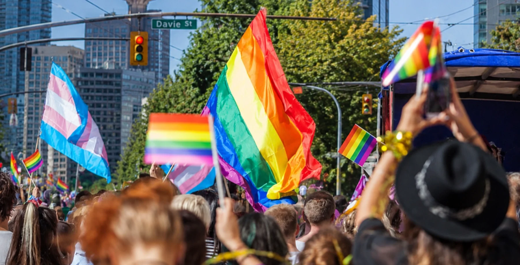 Crowd at Vancouver Pride parade with rainbow flags and celebration.