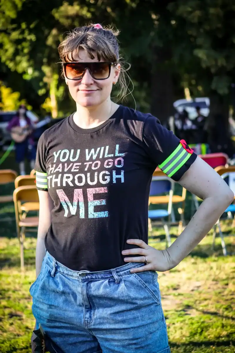 Young woman in sunglasses and casual outfit outdoors at a sunny event.