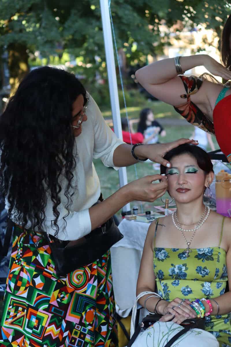 Makeup artist applying makeup to a woman at an outdoor event in Vancouver.