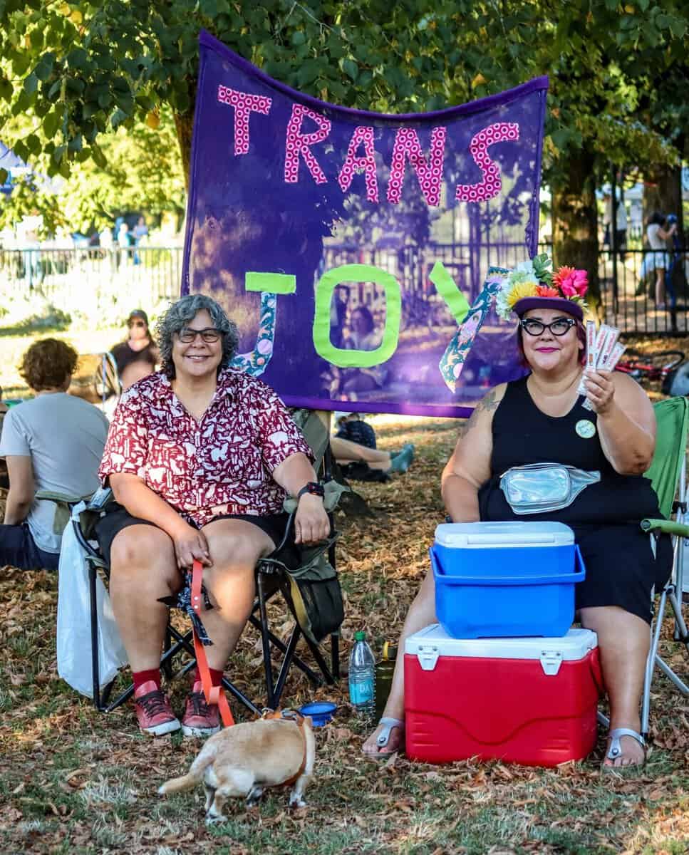 Trans march supporters with colorful banner in Vancouver park.