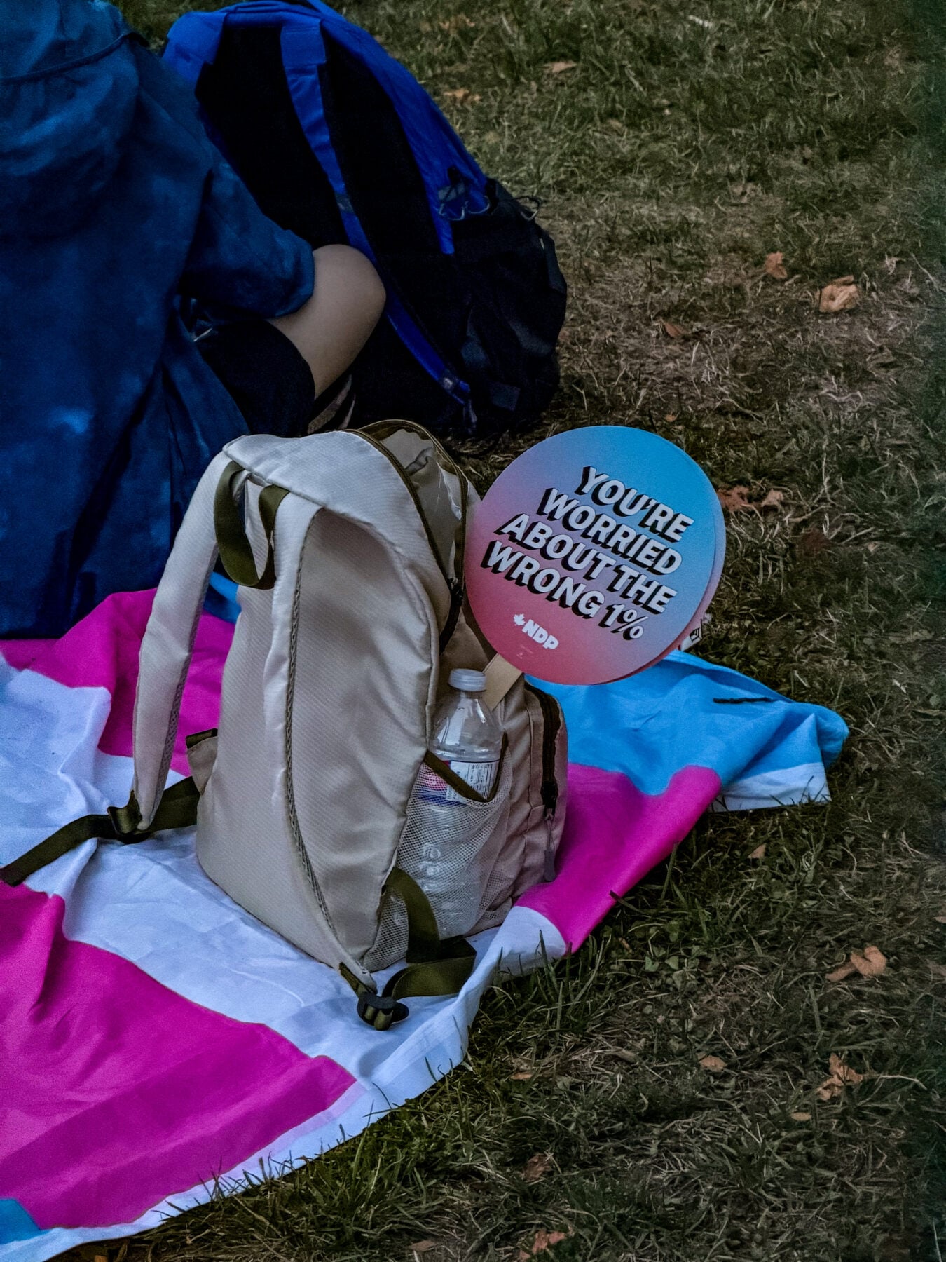 Backpack and protest sign on grass at outdoor event in Canada.