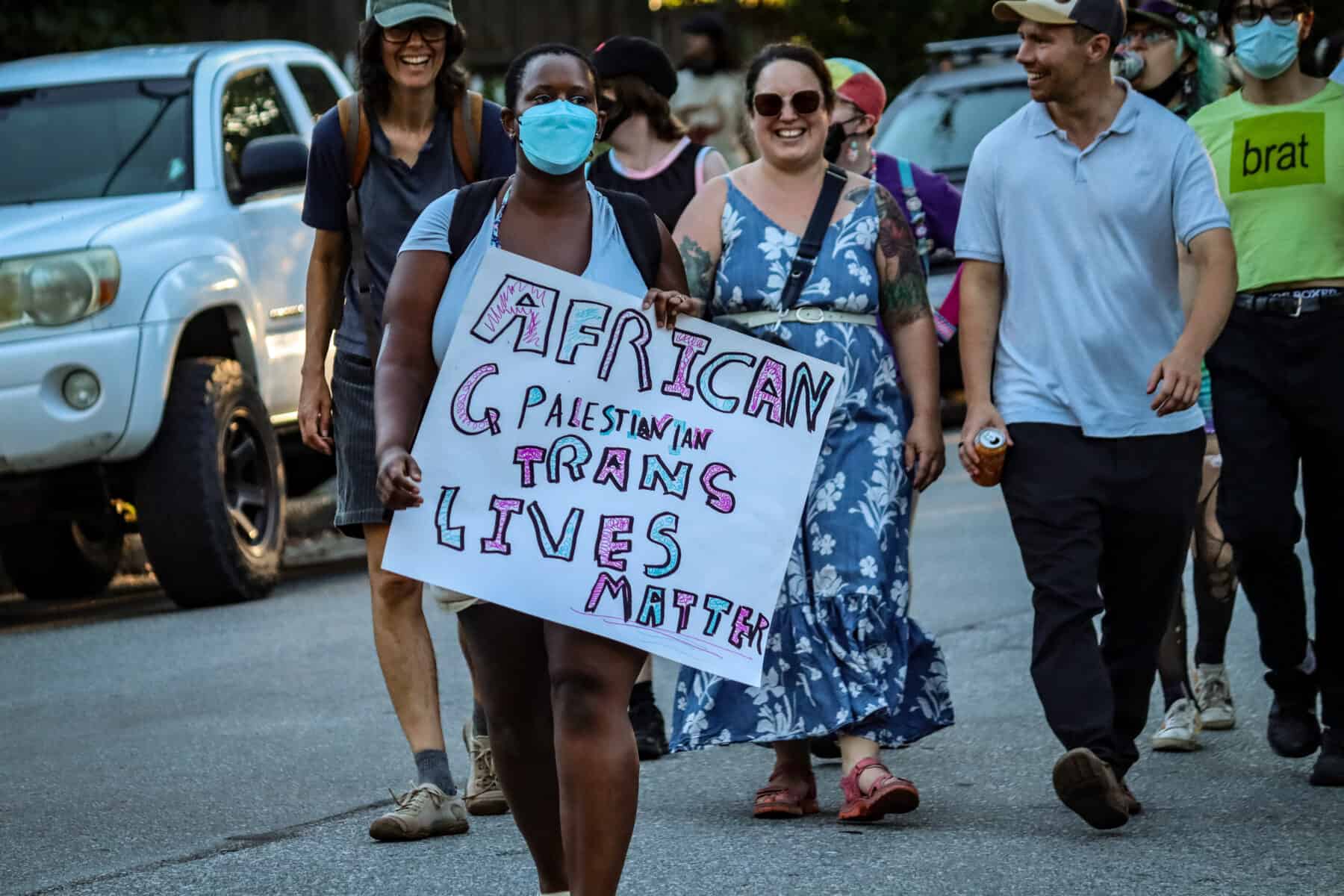 Protesters march during the 2026 Vancouver Trans March holding a sign for trans lives.