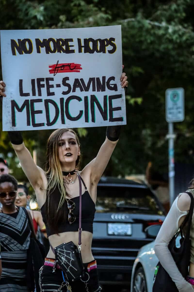 Protester holding sign at Vancouver Trans March advocating for life-saving medicine.