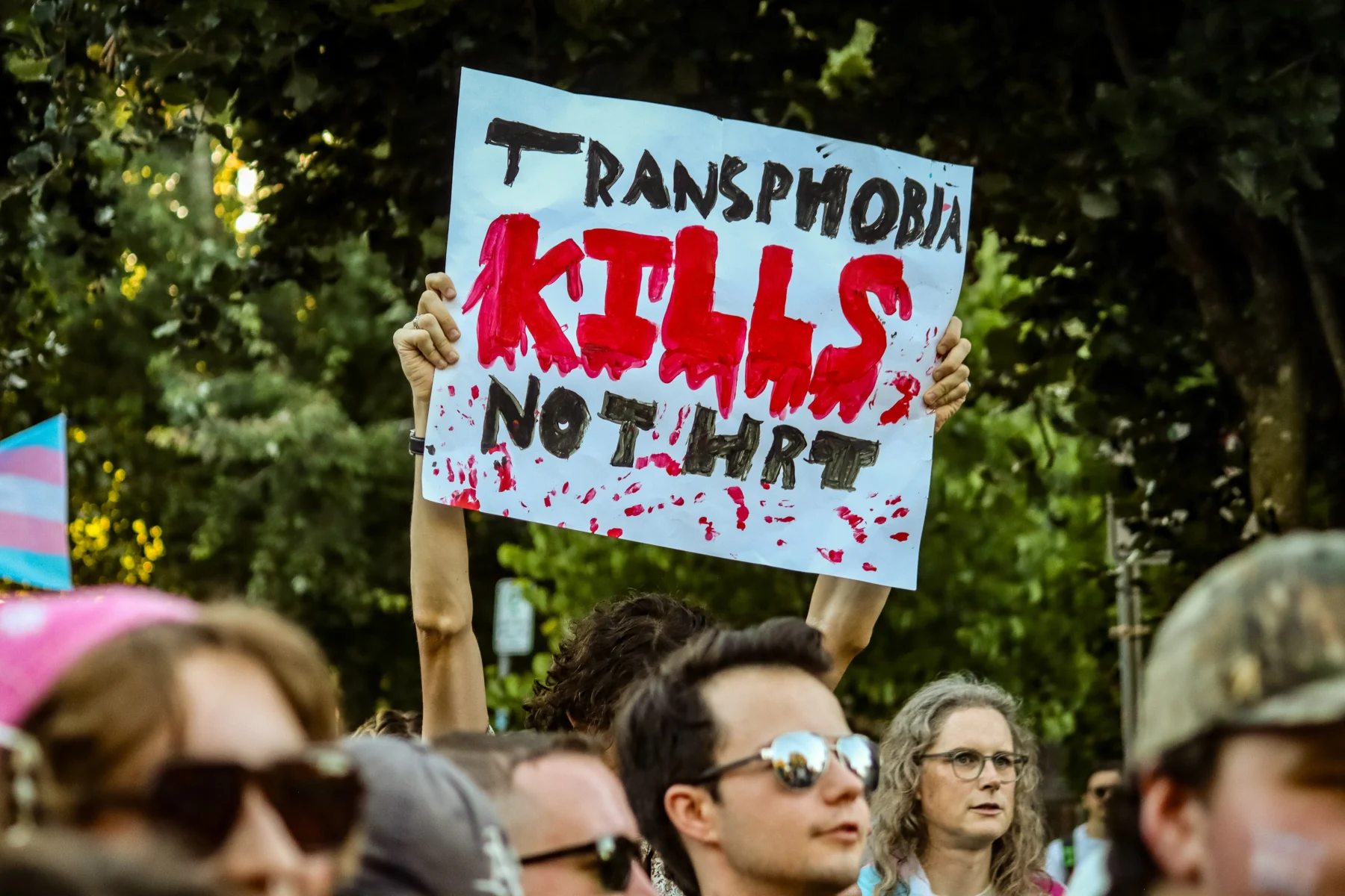 Protest sign reading 'Transphobia kills, not hurt' at rally against discrimination.
