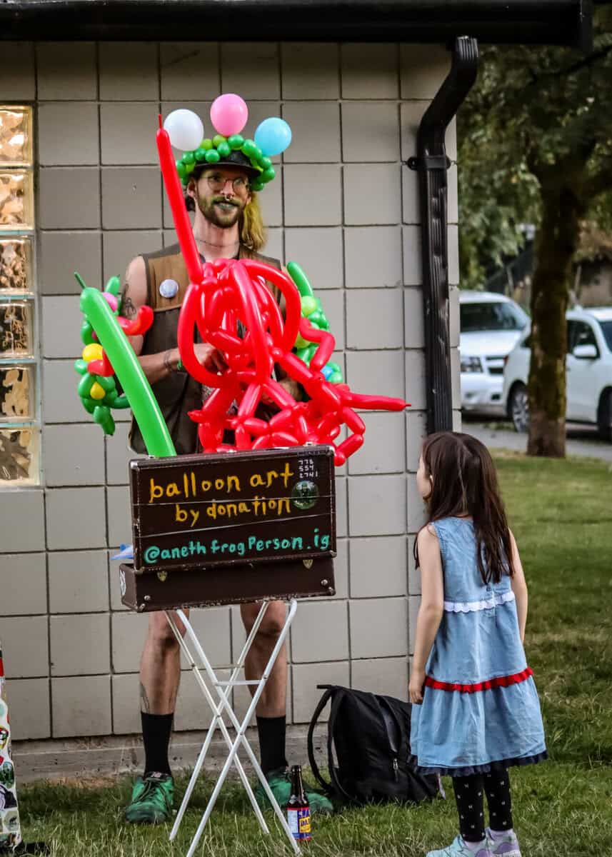 Balloon artist with colorful balloons and a young girl at Vancouver Trans March.