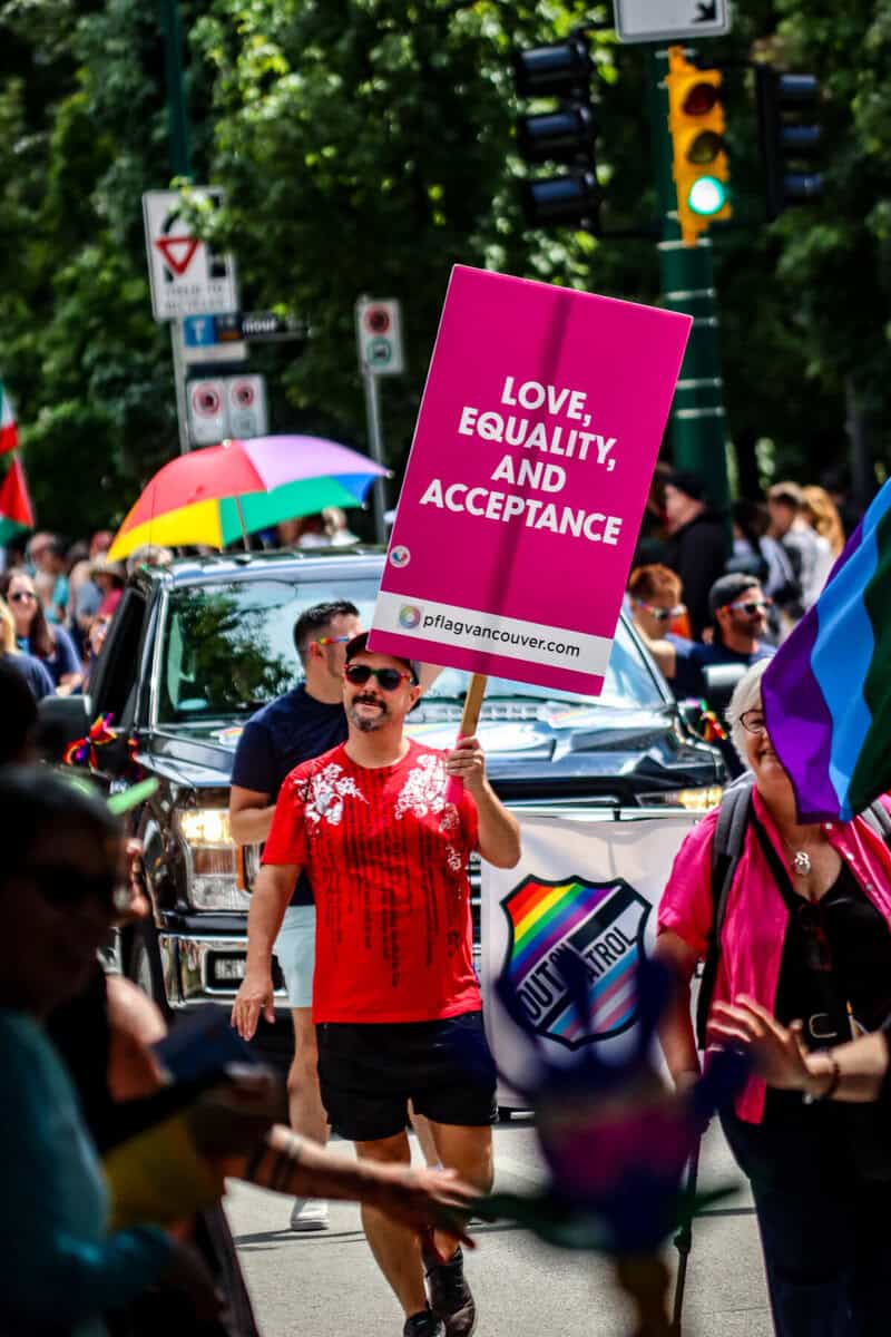 Person holding 'Love, Equality, and Acceptance' sign at pride parade.