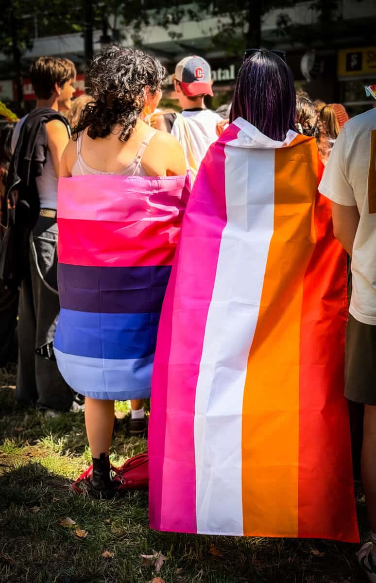 People at a pride event with rainbow and transgender flags in Toronto.