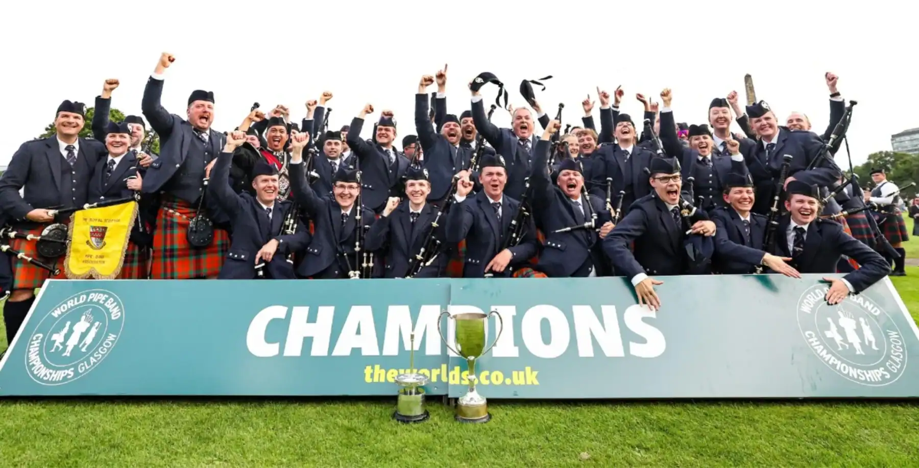 Celebrating champions in traditional Scottish attire at a sports event.
