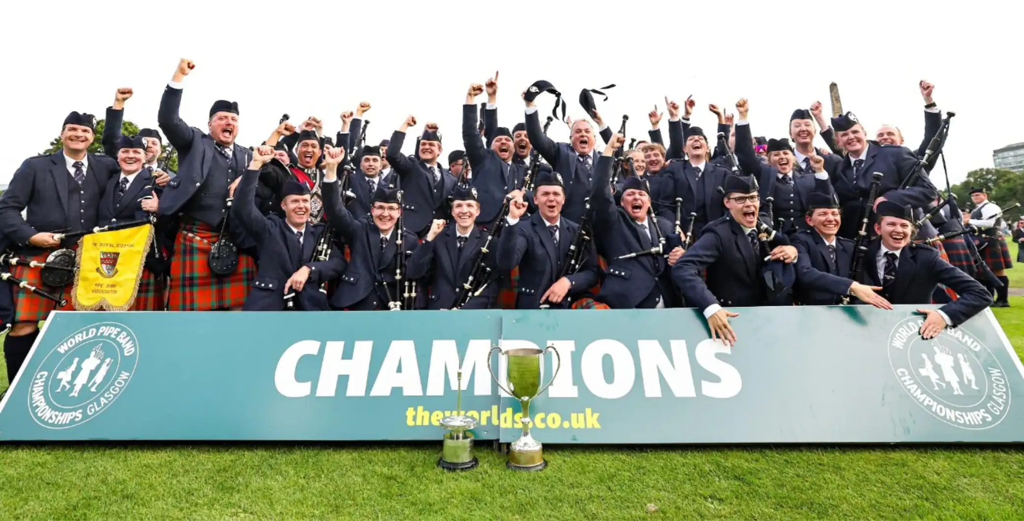 Celebrating champions in traditional Scottish attire at a sports event.