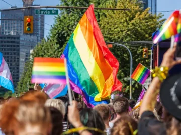 Crowd at Vancouver Pride parade with rainbow flags and celebration.