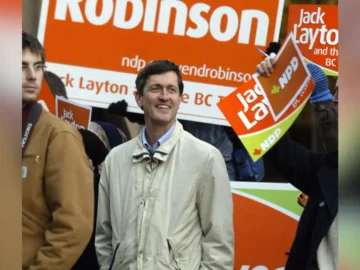 Svend Robinson at a Pride event with campaign signs in the background.