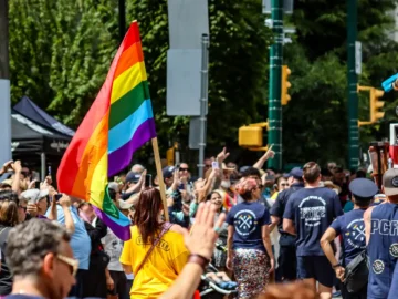 LGBTQ+ pride parade with rainbow flag and diverse crowd in downtown Toronto.