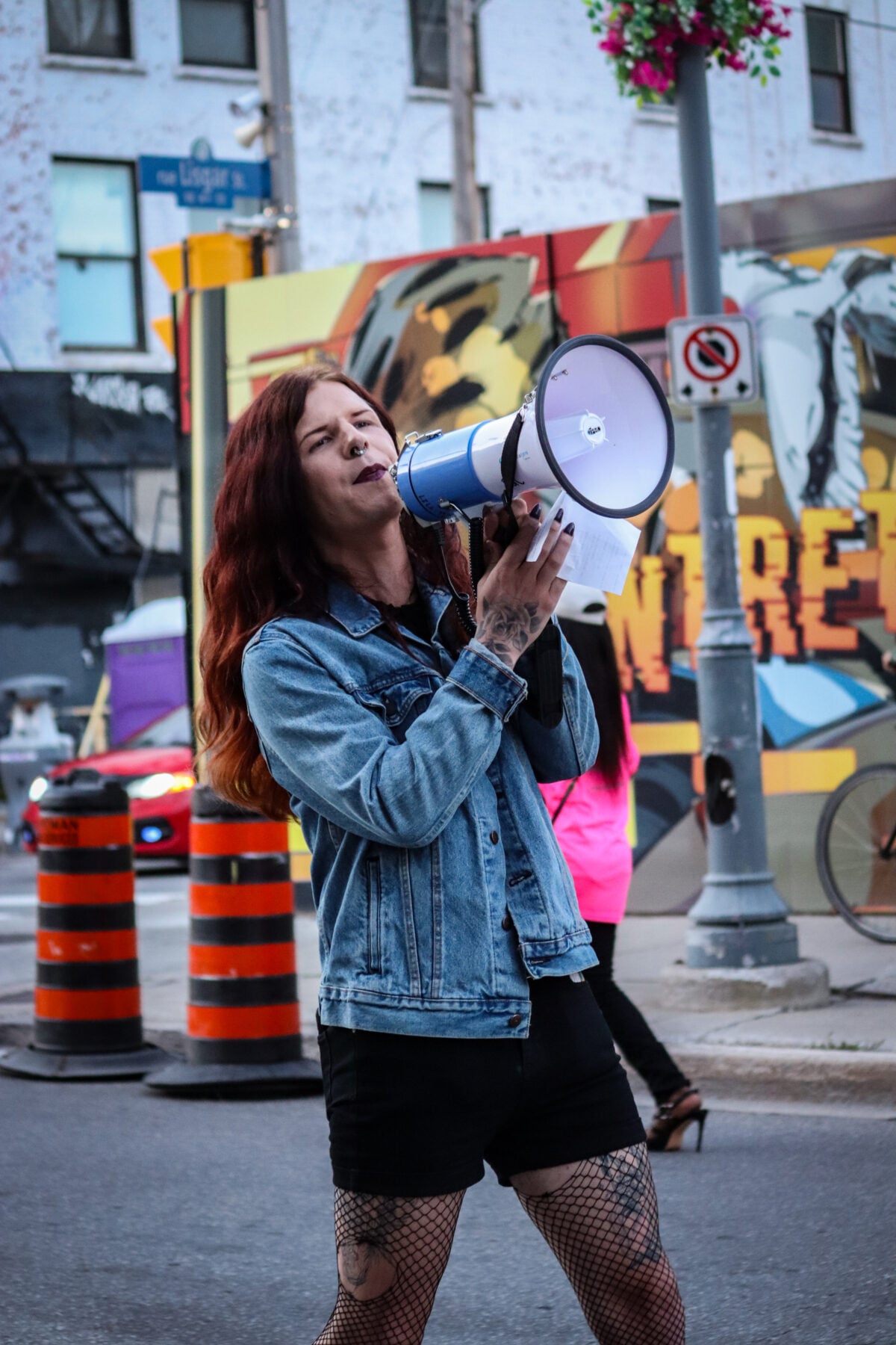 Woman with red hair using a megaphone at a pride march in Ottawa.
