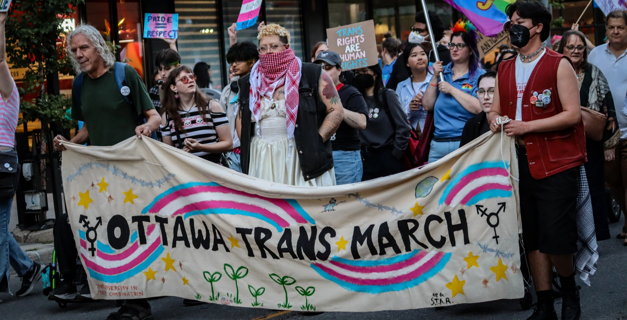 Ottawa Trans March participants holding a banner and signs during the event.