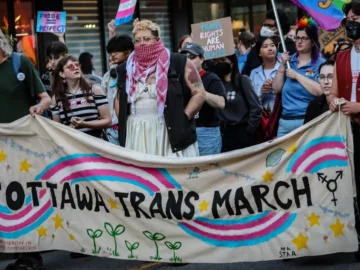 Ottawa Trans March participants holding a banner and signs during the event.